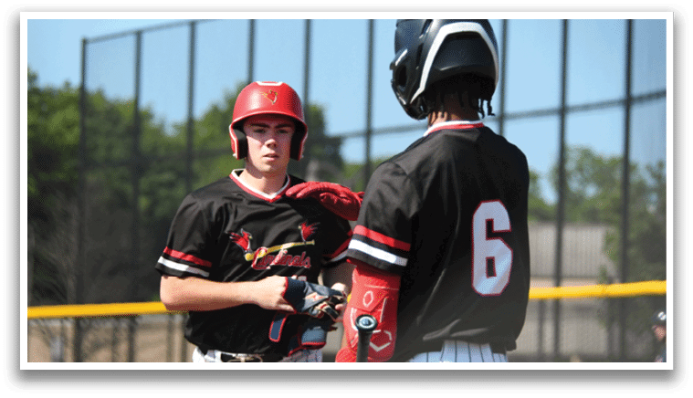 Two baseball players wearing red helmets and black jerseys. Description generated by AI