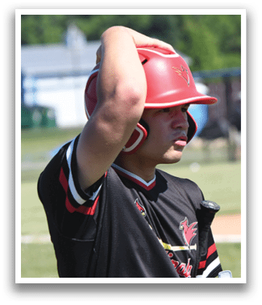 A baseball player wearing a red shirt and white pants stands on a field. Description generated by AI
