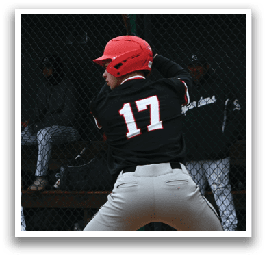 A baseball player in a black shirt and red helmet is holding a bat and waiting for the pitch. Description generated by AI
