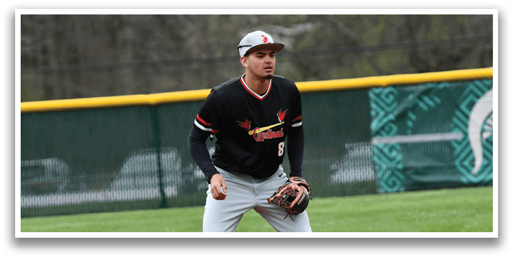 A baseball player in a black and red uniform is standing on a baseball field. Description generated by AI