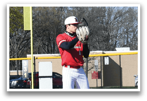 A baseball player in a red and white uniform stands on a pitcher's mound. Description generated by AI