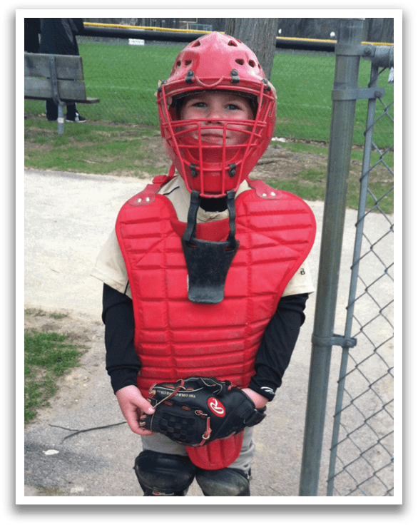 A young boy wearing a baseball helmet and chest protector. AI generated content