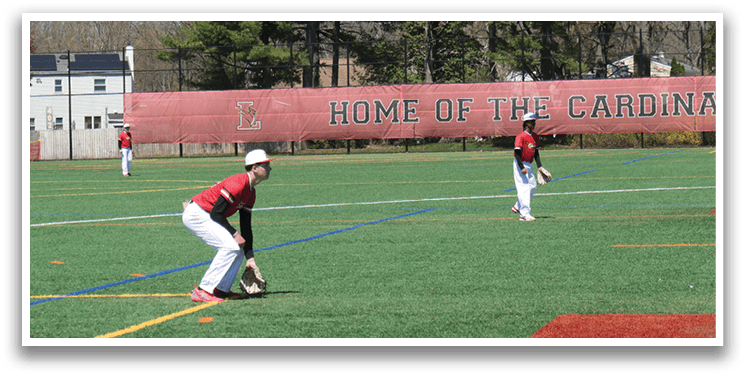 A baseball player in a red shirt and white pants is crouching on the field. Description generated by AI