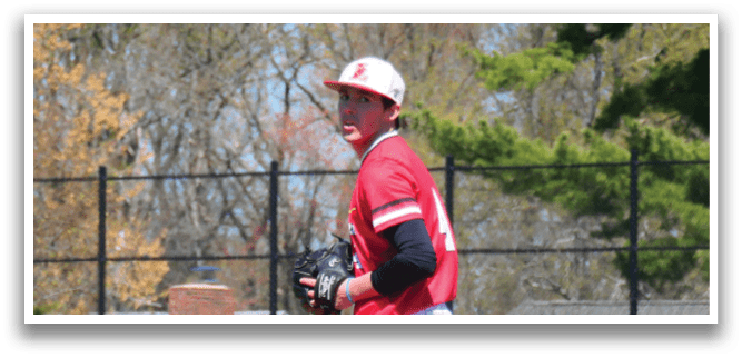 A baseball player in a red shirt and white pants stands on a mound. Description generated by AI