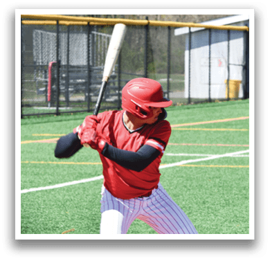 A baseball player in a red shirt and white pants holding a bat. Description generated by AI
