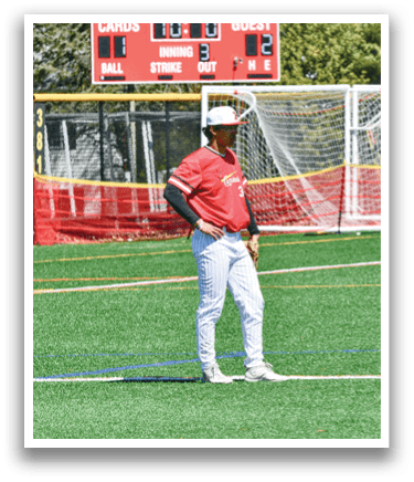 A man wearing a red shirt and white pants standing on a field. Description generated by AI