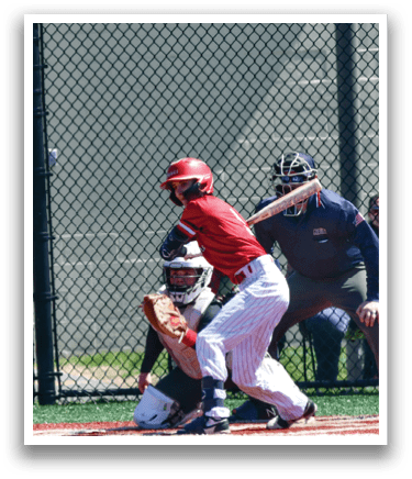 A baseball player in a red shirt and white pants is holding a bat, ready to swing at a ball. Description generated by AI