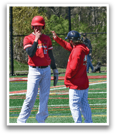 Two men wearing red and white uniforms are standing on a field. Description generated by AI
