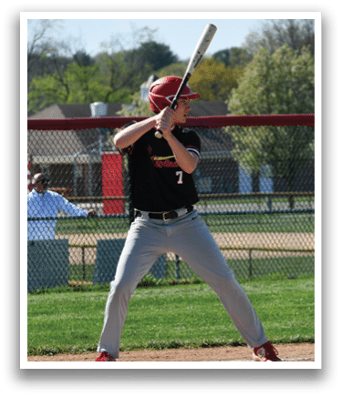 A baseball player in a black shirt and red hat is swinging a bat. Description generated by AI