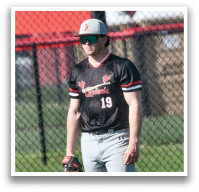 A baseball player wearing a black and red jersey and grey pants. Description generated by AI