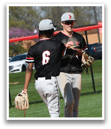 Two baseball players wearing black shirts and white pants. Description generated by AI