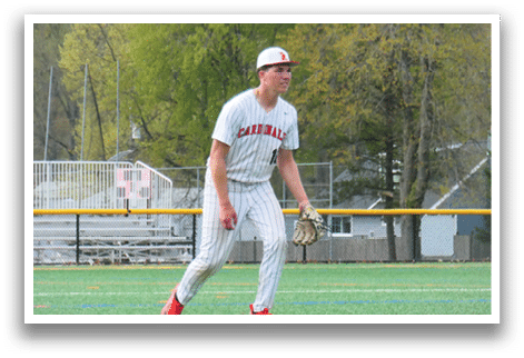 A baseball player in a white and red uniform stands on a baseball field. Description generated by AI
