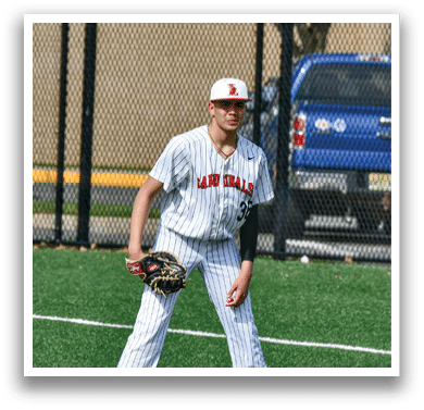 A baseball player in a white uniform stands on a baseball field. Description generated by AI
