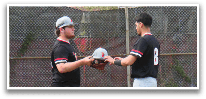 Two men are talking to each other in a baseball field. Description generated by AI
