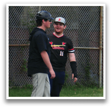 Two men wearing baseball uniforms are talking to each other. Description generated by AI
