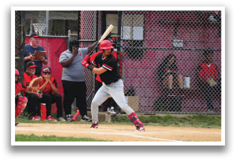 A baseball player in a black shirt and red hat is swinging a bat. Description generated by AI