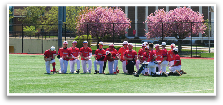 A group of people wearing red and white uniforms are sitting on a grassy field. Description generated by AI