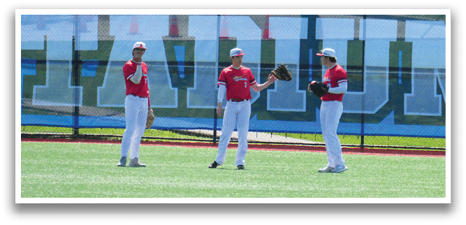 Three baseball players standing on a field. Description generated by AI