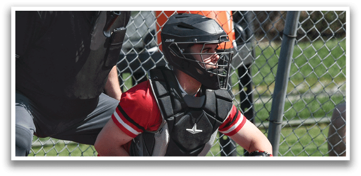 A baseball catcher wearing a helmet and chest protector. Description generated by AI