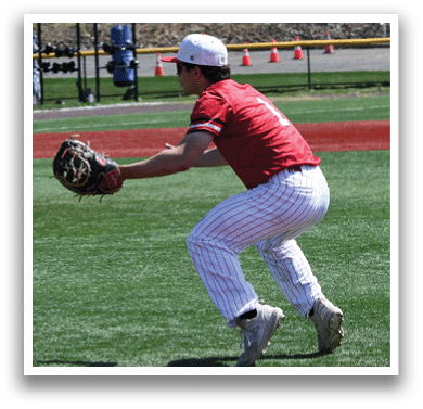 A baseball player in a red and white uniform is bending over to catch a ball. Description generated by AI