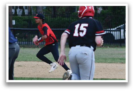 A baseball player wearing a red and black jersey is running towards a base. Description generated by AI