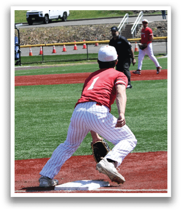 A baseball player in a red and white striped uniform is bending over to catch a ball. Description generated by AI