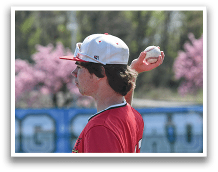 A man wearing a red shirt and a white hat is holding a baseball. Description generated by AI