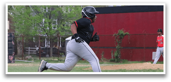 A man wearing a black shirt and grey pants running on a baseball field. Description generated by AI