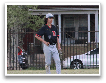 A man wearing a baseball uniform stands in a grassy field. Description generated by AI