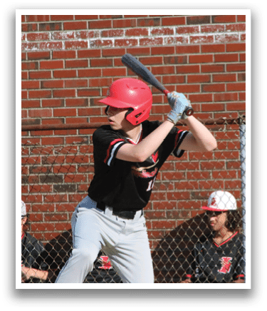 A baseball player in a red helmet and black shirt is swinging a bat. Description generated by AI
