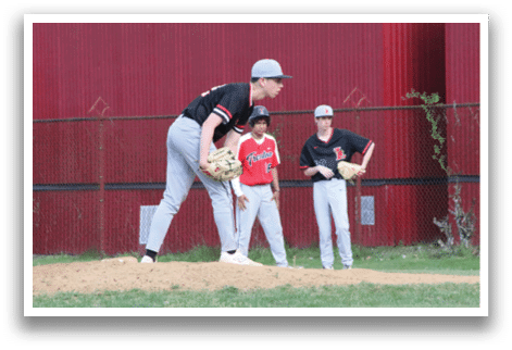 A baseball player in a black shirt and white hat is pitching a ball. Description generated by AI