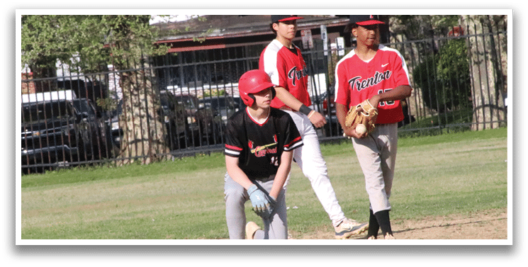 A boy in a red baseball cap and black shirt is standing on a baseball field. Description generated by AI