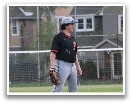 A boy wearing a baseball uniform is standing on a grassy field. Description generated by AI