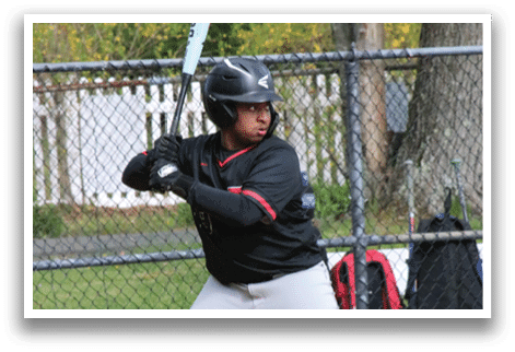 A baseball player in a black shirt and grey pants is swinging a bat. Description generated by AI