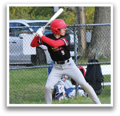 A baseball player in a red helmet and black shirt is swinging a bat. Description generated by AI