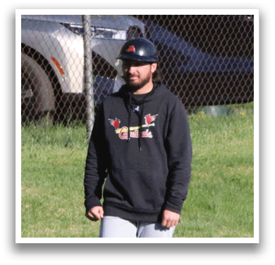 A man wearing a black hoodie and grey pants standing on a grassy field. Description generated by AI