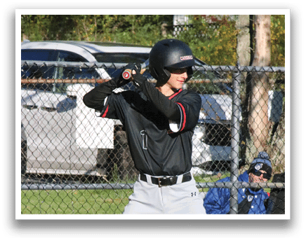 A baseball player in a black and red shirt is holding a bat and getting ready to swing. Description generated by AI