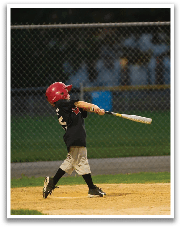A young boy is swinging a baseball bat on a field. AI generated content