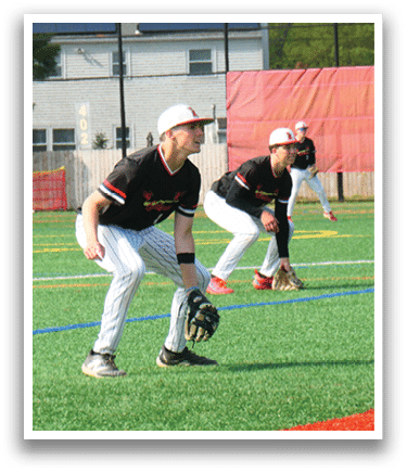 A baseball player in a black shirt and white pants is crouching down with a baseball glove. Description generated by AI