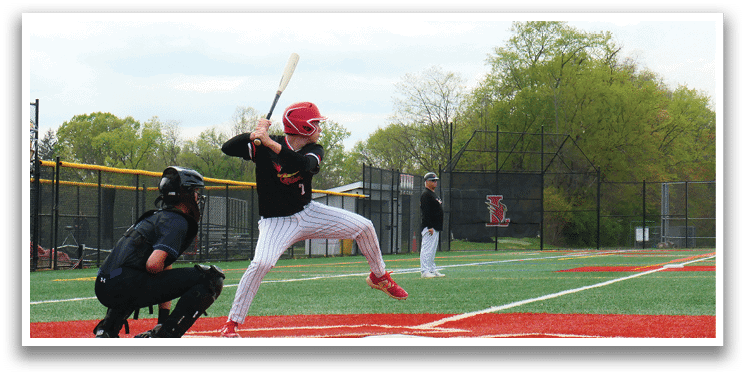 A baseball player in a black shirt and red shoes is swinging a bat. Description generated by AI