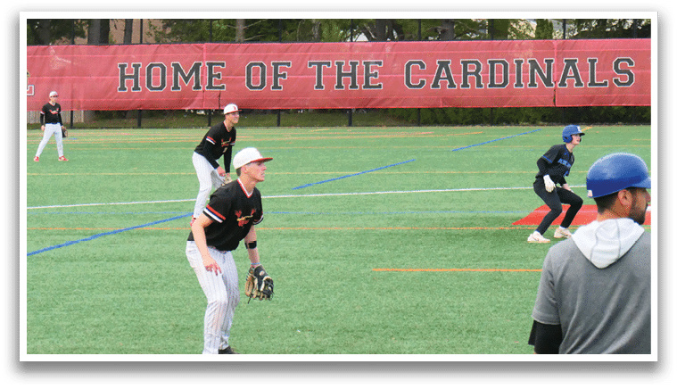 A baseball game is being played on a field with a red banner. Description generated by AI