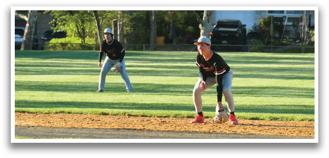 A baseball player in a black shirt and red shoes is ready to catch a ball. Description generated by AI
