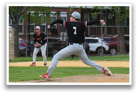 A baseball player in a black shirt and red shoes is pitching a ball. Description generated by AI
