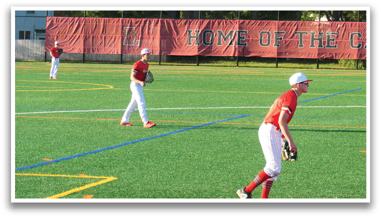 A baseball player in a red shirt and white pants is standing on a field. Description generated by AI