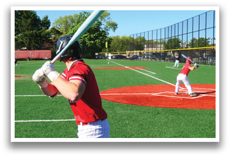 A baseball player in a red shirt and white pants holding a bat. Description generated by AI