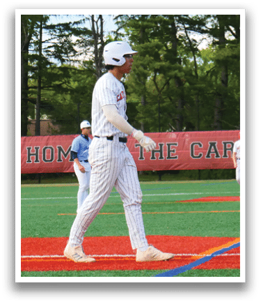 A baseball player is standing at home base, wearing a white uniform. Description generated by AI