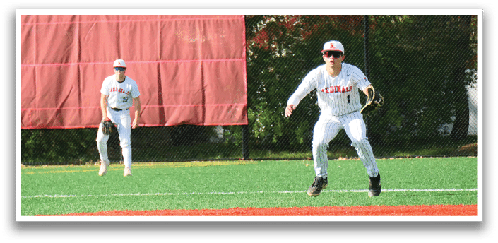 A baseball player in a white uniform is standing on a field. Description generated by AI