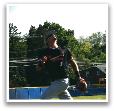 A man wearing a black shirt and grey pants catching a ball. Description generated by AI