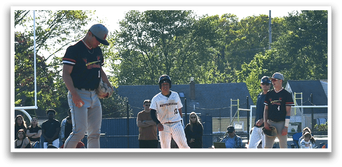 A baseball game is taking place with a man in a black shirt and hat pitching the ball. Description generated by AI