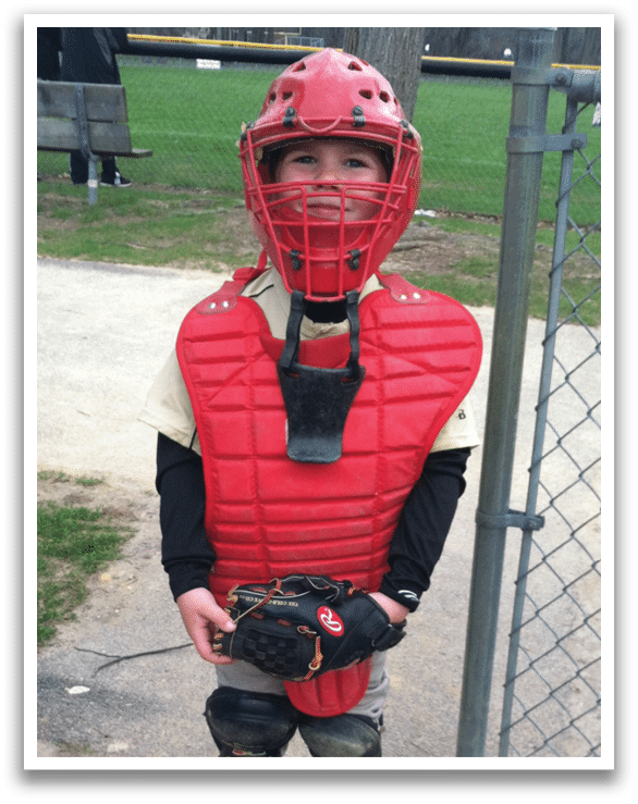 A young boy wearing a baseball helmet and chest protector. AI generated content
